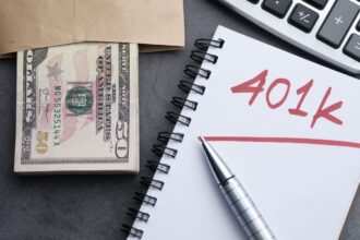 401(k) – notebook labeled 401k with cash, a pen and a calculator