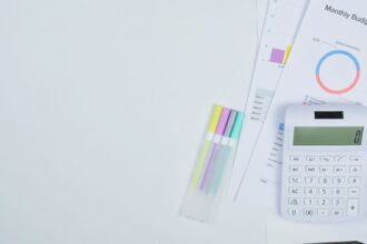 50/30/20 rule – minimalist office desk with a calculator, budget planning documents and colorful pens