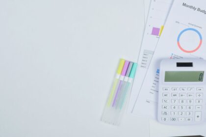 50/30/20 rule – minimalist office desk with a calculator, budget planning documents and colorful pens