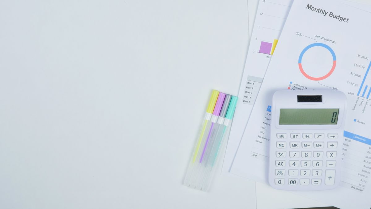 50/30/20 rule – minimalist office desk with a calculator, budget planning documents and colorful pens