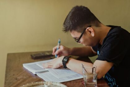 Budget in college – college student taking notes at his desk