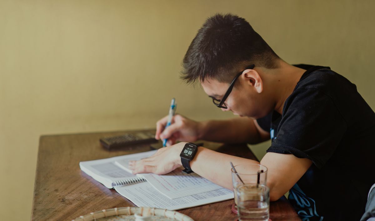 Budget in college – college student taking notes at his desk