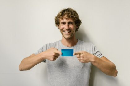 Build credit at 18 – cheerful young man holding a blue credit card