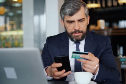 Business bank account – business owner using a phone and card for online banking