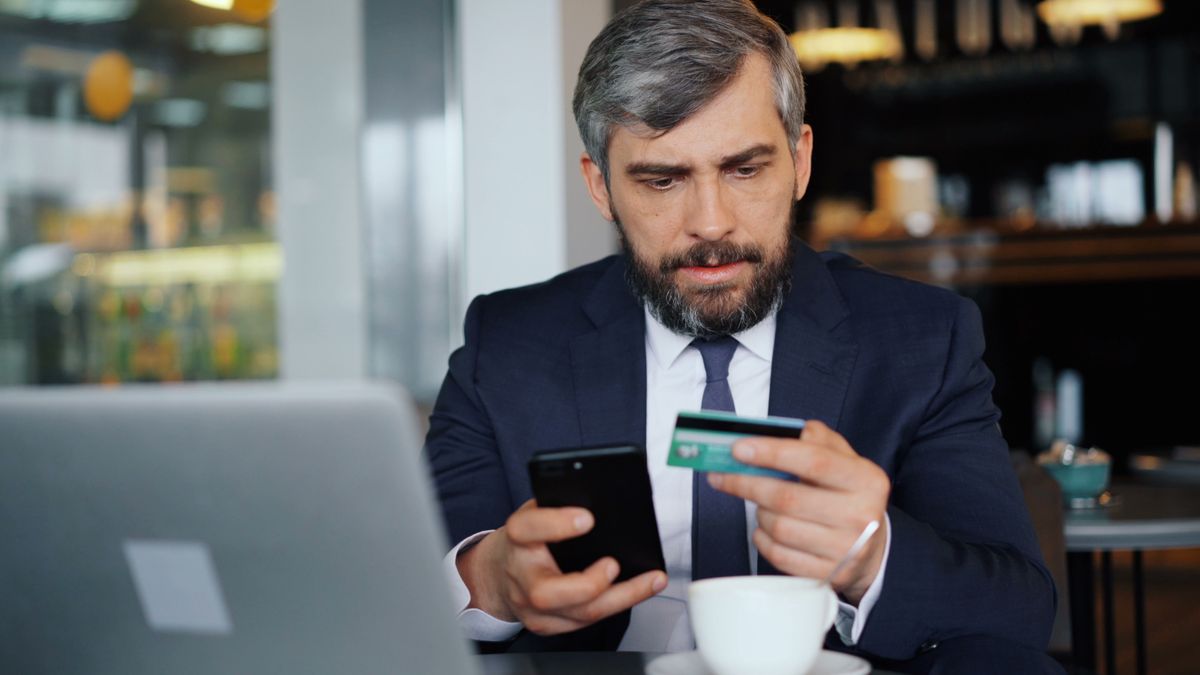 Business bank account – business owner using a phone and card for online banking