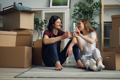 Buy a house with student loans – smiling young couple on moving day in their new home