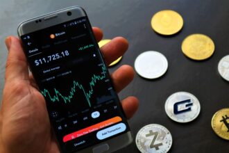 Buy crypto safely – smartphone app showing Bitcoin trading details beside crypto coins