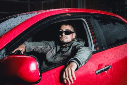 Car insurance for young drivers – young driver in sunglasses sitting in a red car