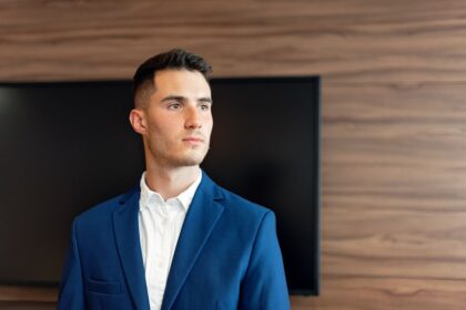 CEO in your 20s – confident young businessman in a blue suit in a modern office