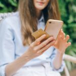 Check your credit score for free – woman using a smartphone while holding a credit card