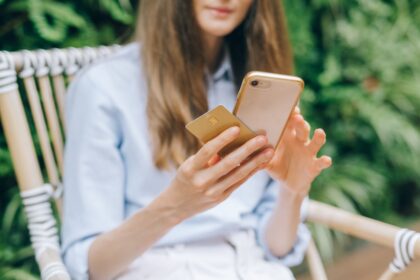 Check your credit score for free – woman using a smartphone while holding a credit card