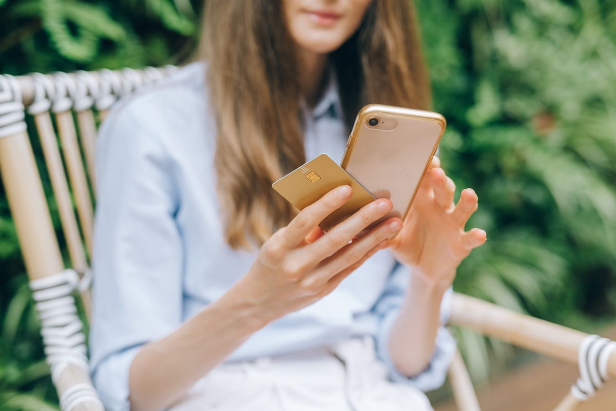 Check your credit score for free – woman using a smartphone while holding a credit card