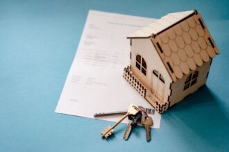 FHA vs conventional loan – miniature wooden house with keys and a mortgage contract
