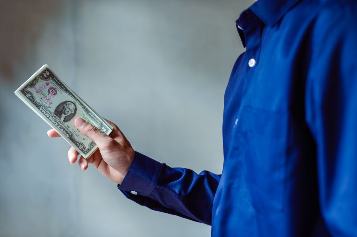 First paycheck – young professional holding a stack of US dollar bills
