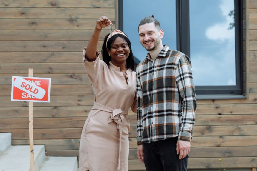 First-time home buyer programs – young couple celebrating buying their first house with keys in hand