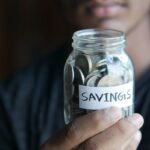 High-yield savings account – hand holding a jar full of coins labeled Savings