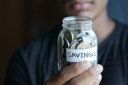 High-yield savings account – hand holding a jar full of coins labeled Savings