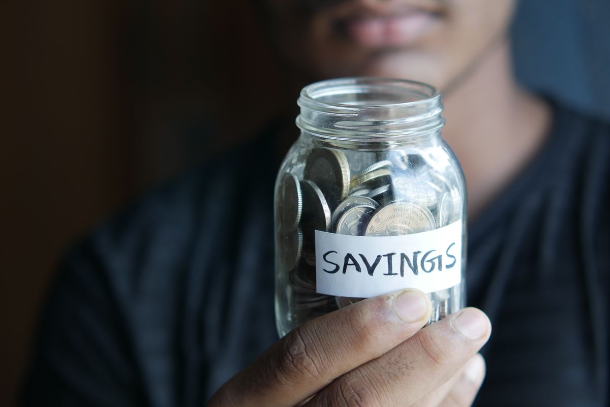 High-yield savings account – hand holding a jar full of coins labeled Savings
