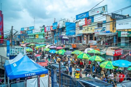 How to invest in Nigeria – busy market street with colorful umbrellas and billboards in Lagos, Nigeria