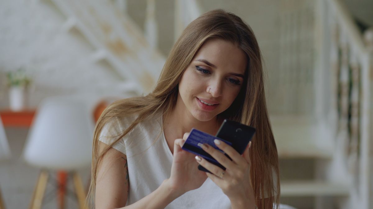 Open a bank account – young woman using a banking app and card at home