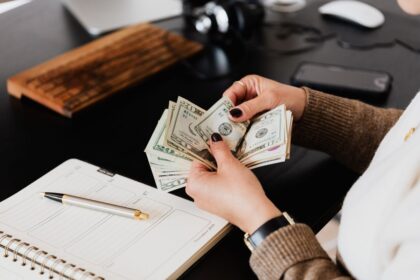 Pay yourself as a business owner – person counting cash next to a planner