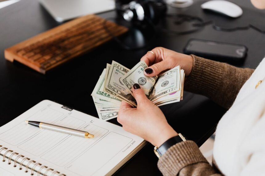 Pay yourself as a business owner – person counting cash next to a planner