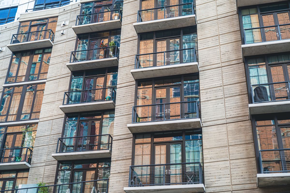 REITs – contemporary apartment building exterior with concrete facade and glass balconies