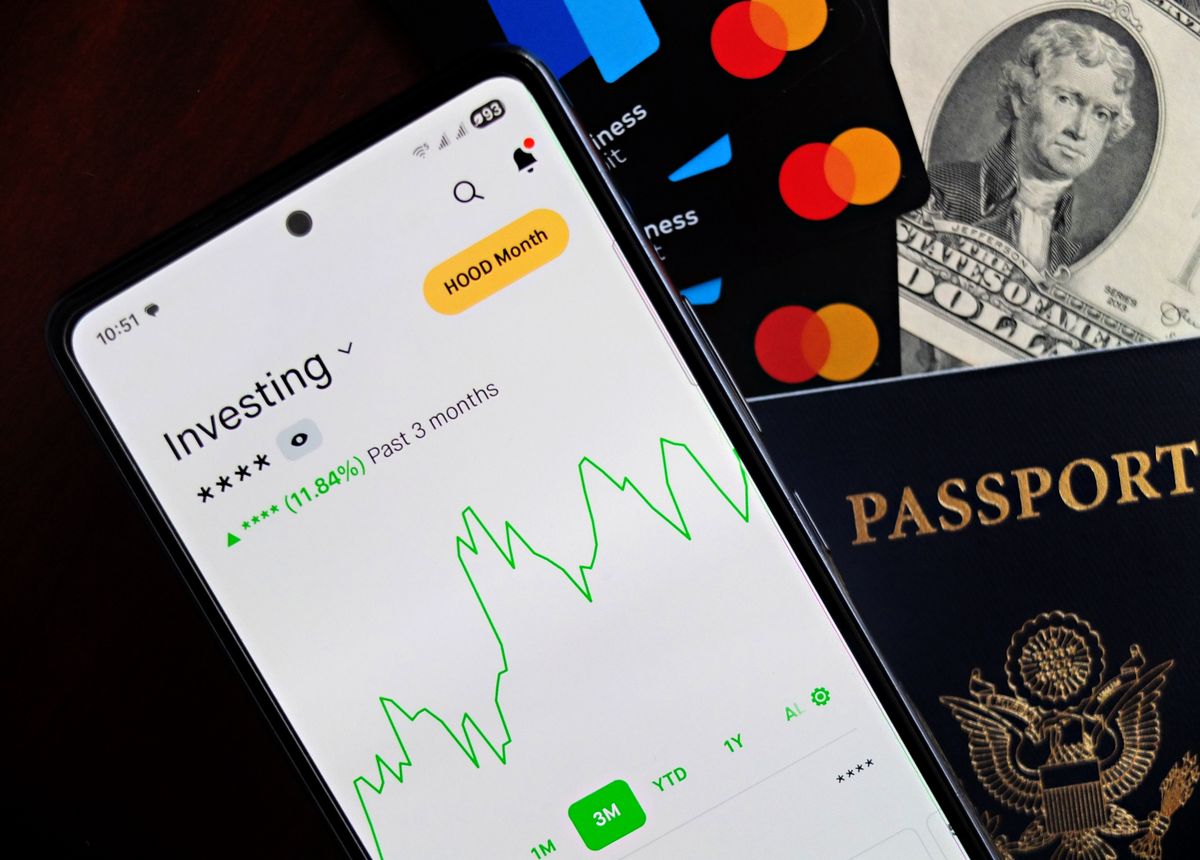 Robo-advisor – smartphone showing an investing app beside cards and cash