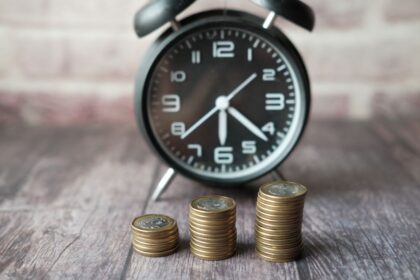 Roth IRA vs Traditional IRA – stacked coins and an alarm clock showing the value of time and money
