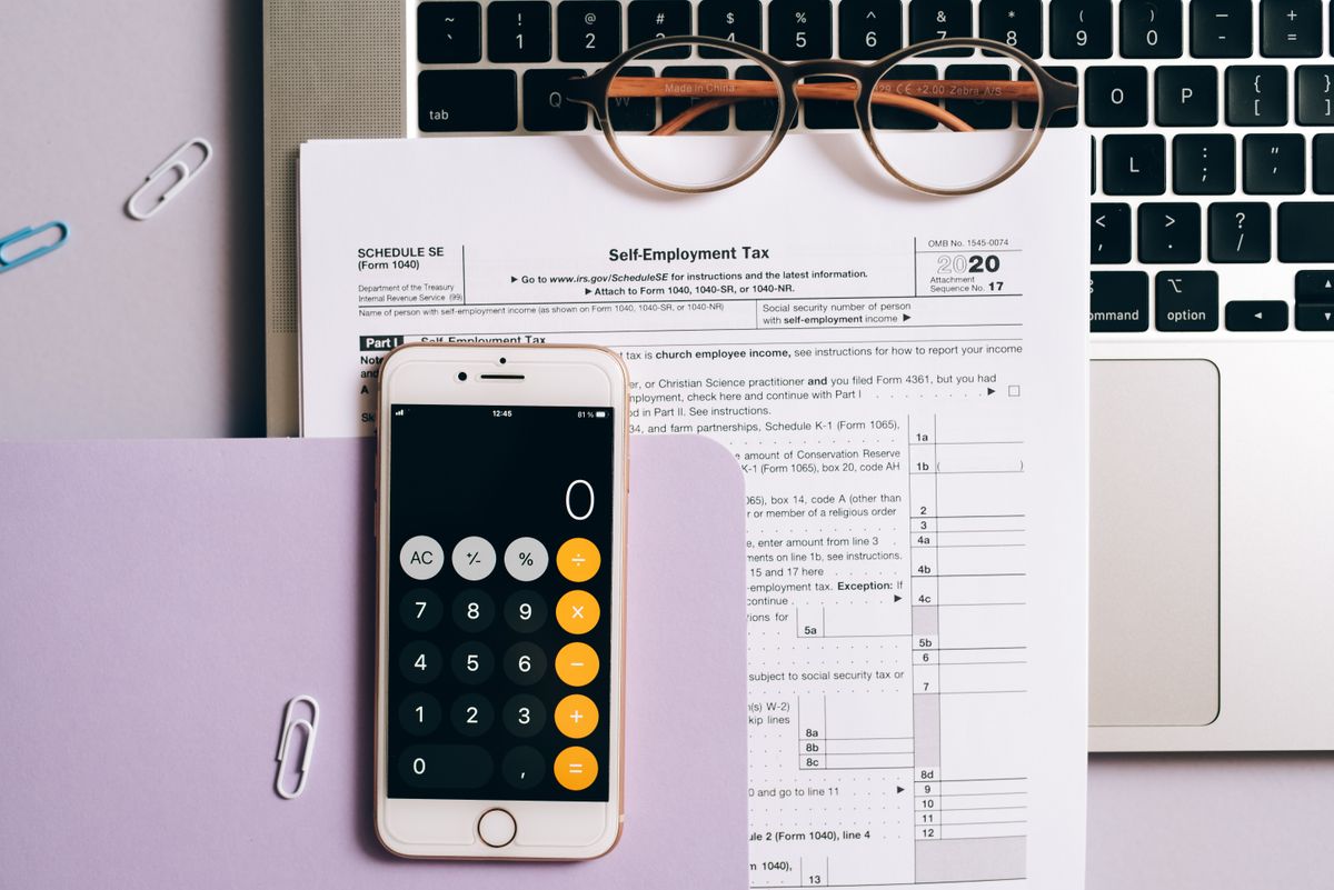 Self Assessment tax return – tax documents, a calculator app and a laptop for self-employed accounts
