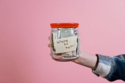 Sinking funds – hand holding a glass jar of dollar bills saved for future plans