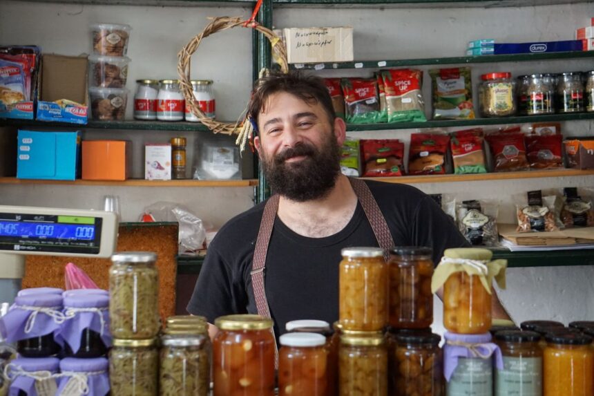 Small business loan – a friendly shopkeeper stands behind shelves of homemade preserves